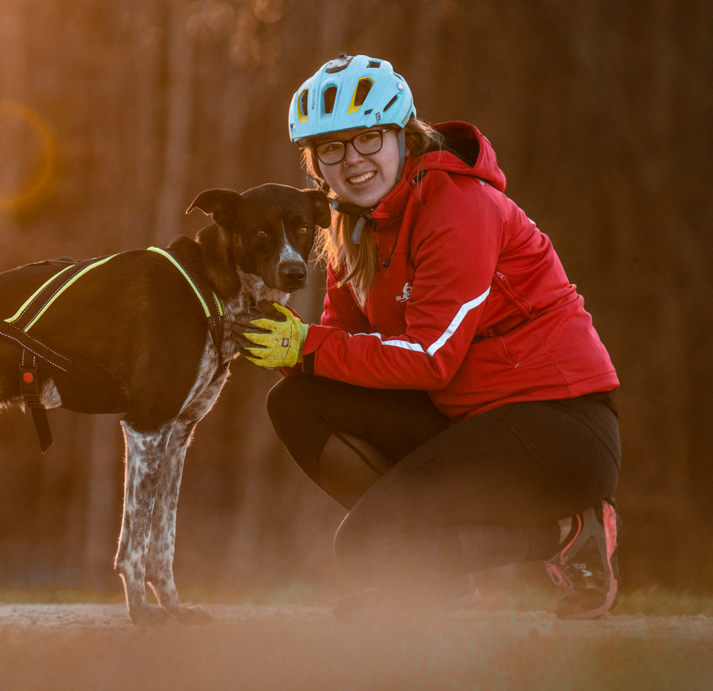 schwarz/weißer Hound mit neongelb Xback Active G3 und Frau mit Fahrradhelm